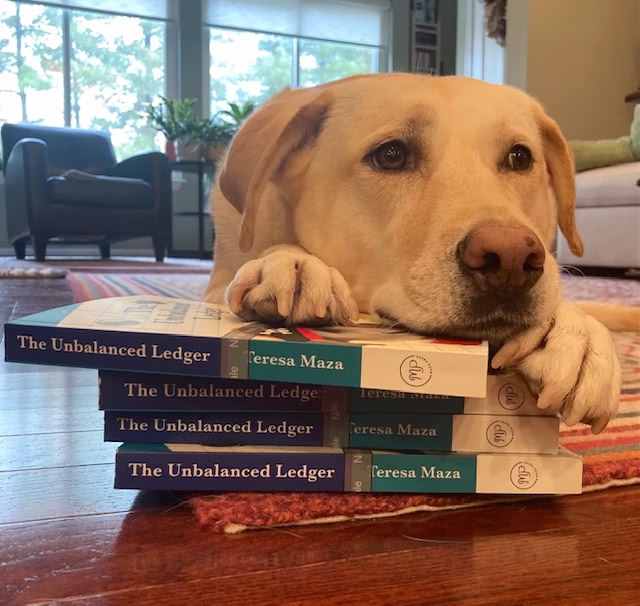 Trusty Dog Sansa A close-up shot of a patient-looking yellow Labrador resting her chin and paws gently on a small stack of four books titled, "The Unbalanced Ledger," on a colorful rug in a bright living room.